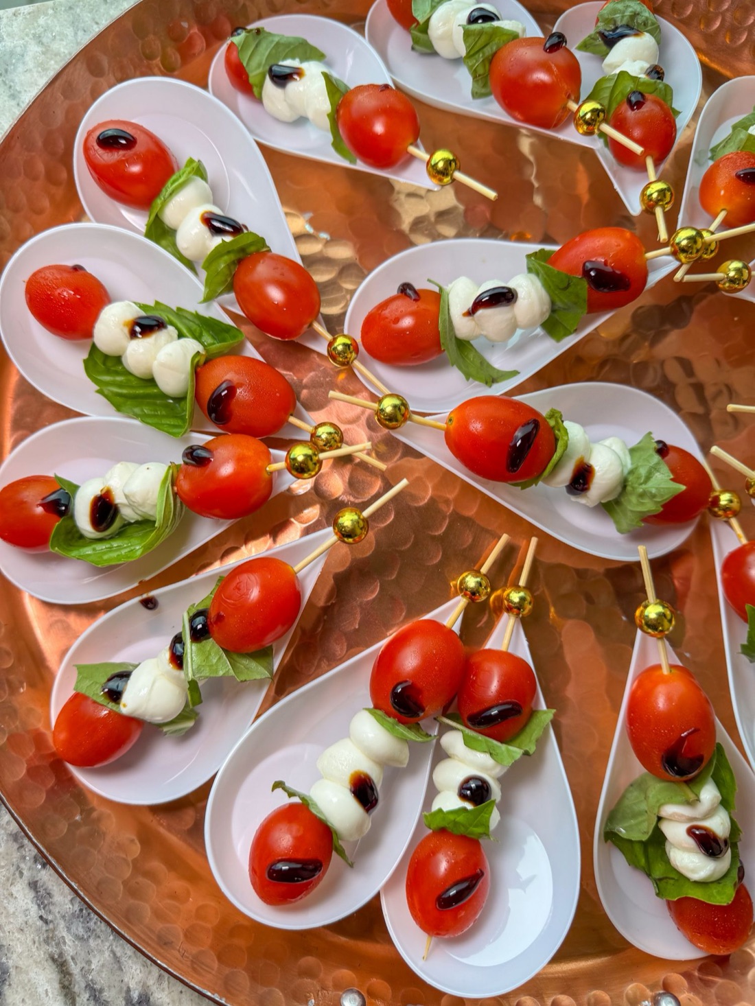 Caprese skewers with cherry tomatoes, mozzarella, basil and balsamic glaze in tasting spoons