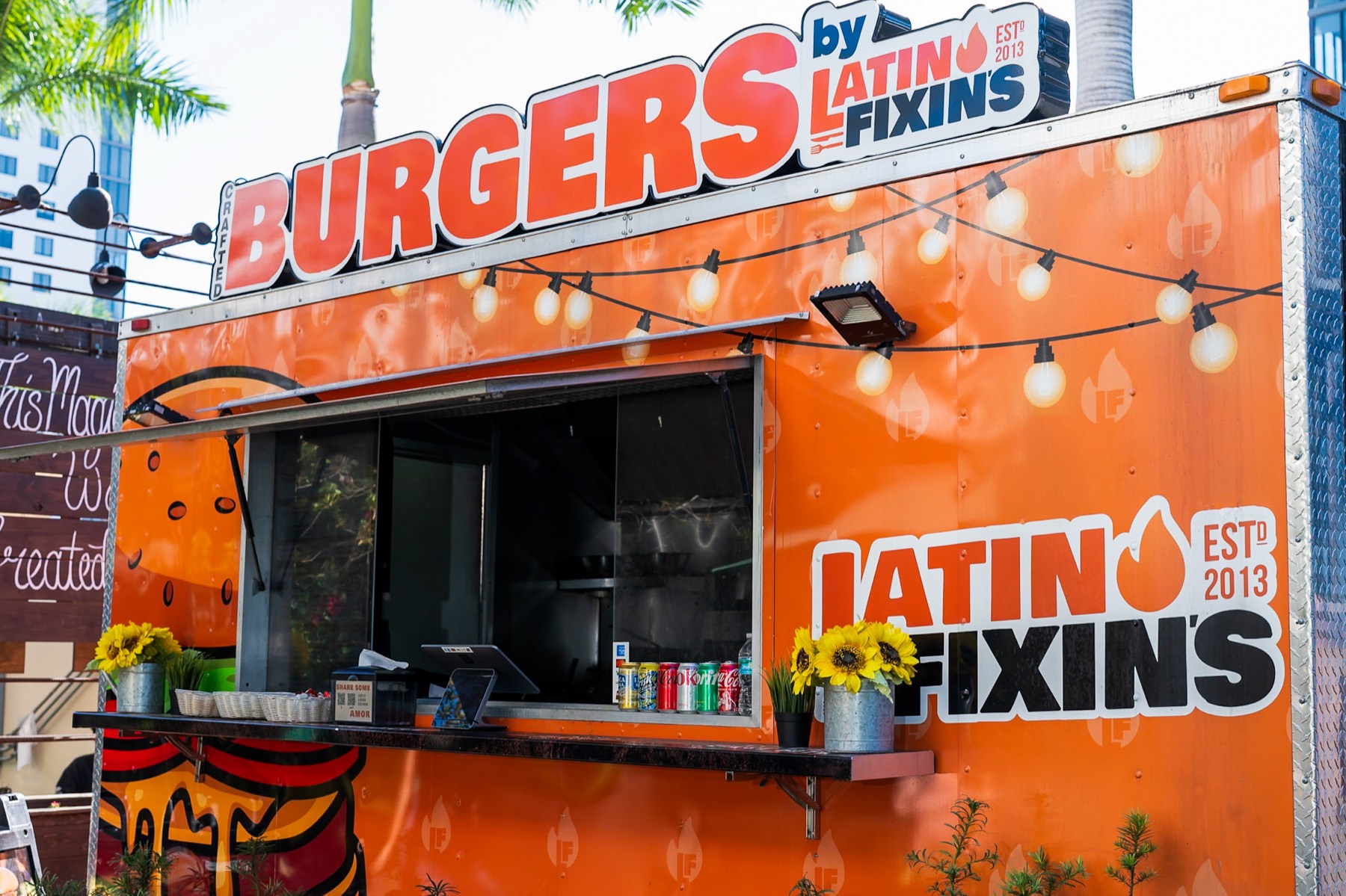 The Latin Fixin's crafted burgers truck parked at The Doral Yard, string lights and sunflowers on the counter